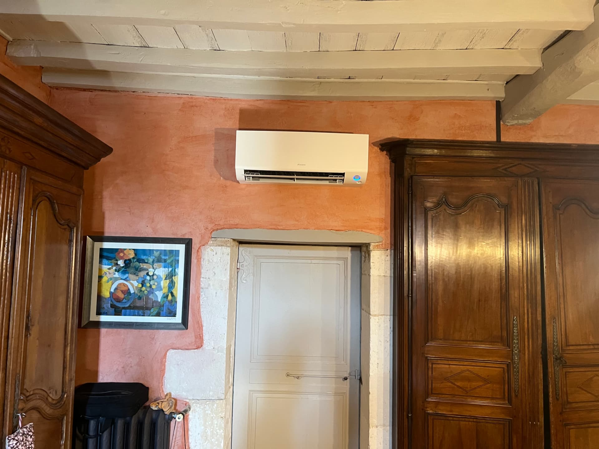 Climatiseur Daikin installé au-dessus d'une porte ancienne